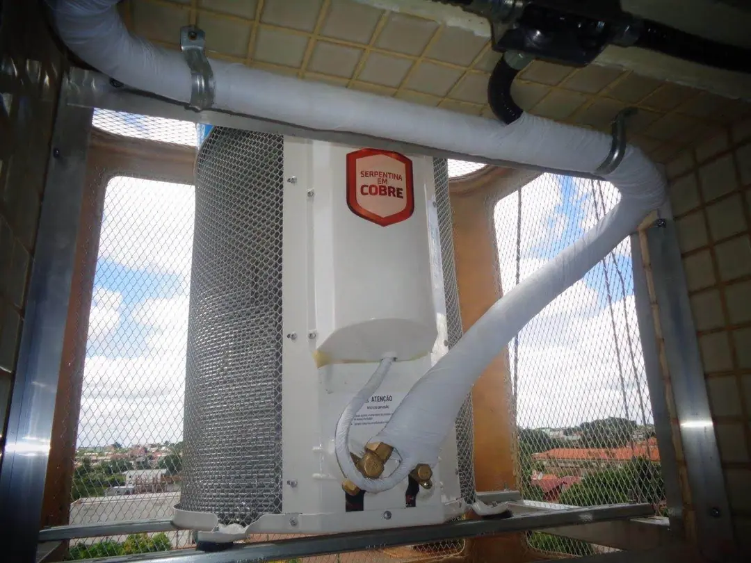 Condensadora instalada em suporte com tela de proteção no alto de um prédio