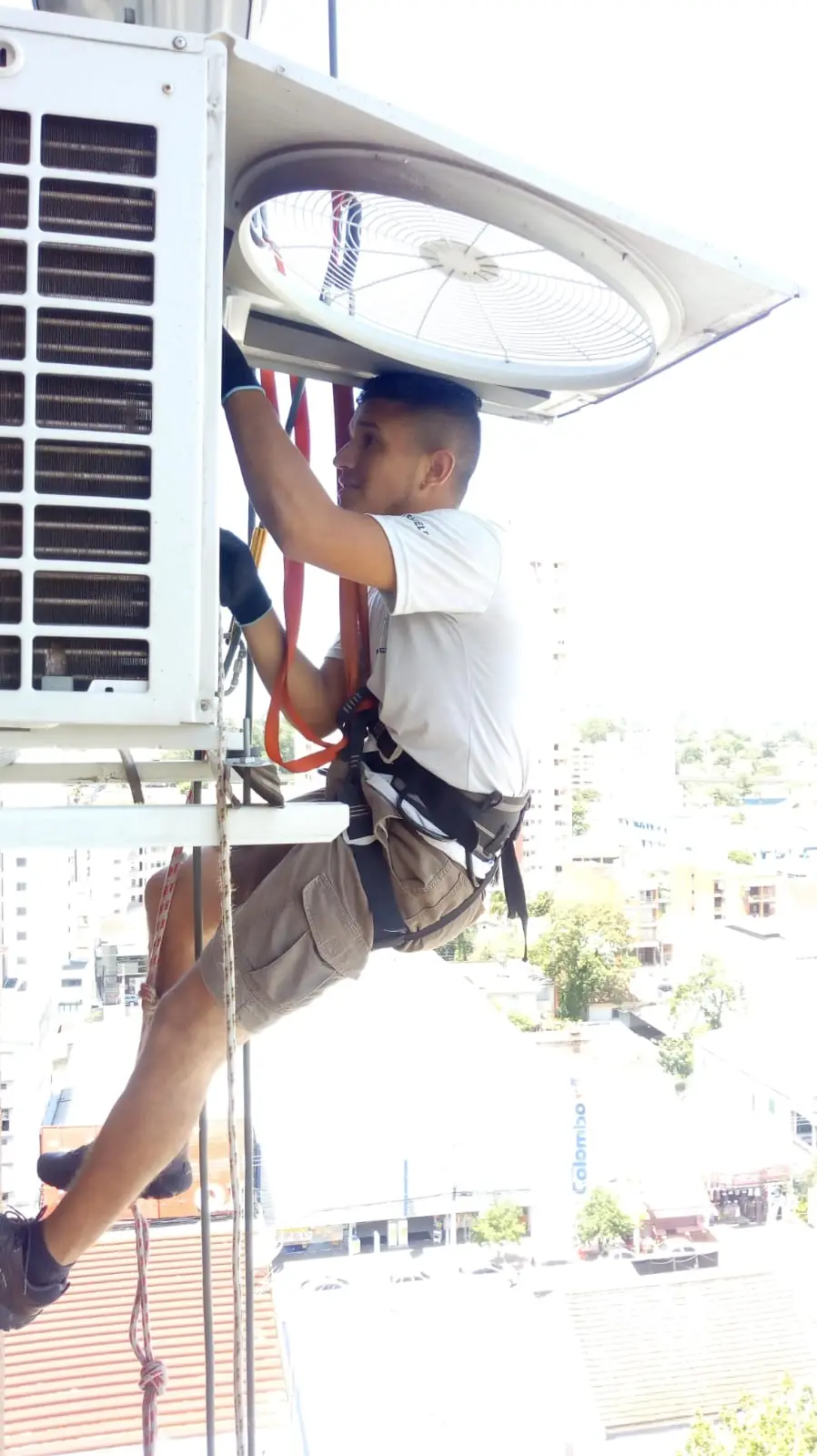Técnico da A&L Service de rapel na fachada de um prédio, instalando uma condensadora